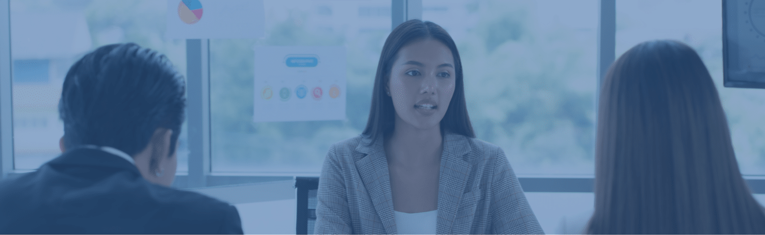A woman in a blazer leading a discussion with two colleagues in a modern office, emphasizing executive coaching.