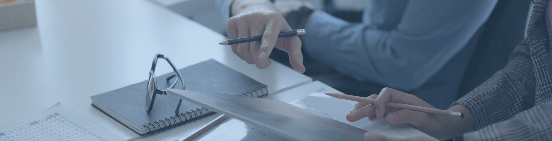 Two professionals collaborating over documents and a tablet on a desk, highlighting C level succession through strategic planning and discussion in a corporate setting.